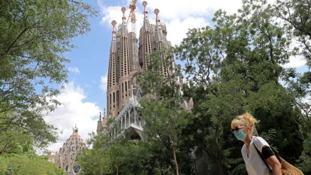 Mulher de máscara passando pela Sagrada Família