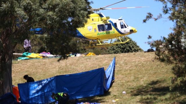 Um helicóptero de ambulância visto ao lado de uma lona em uma colina