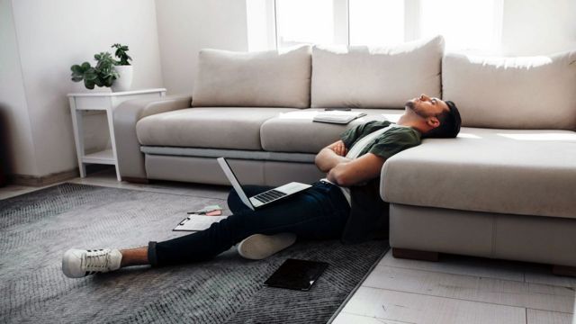 Homem deitado de braços cruzados em frente ao laptop
