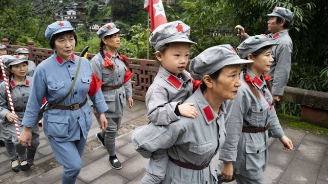 Crianças e adultos com uniformes caminhando, a aparentemente sobre ponte