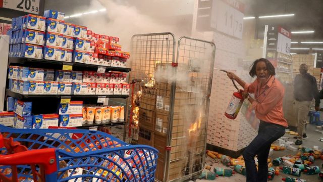 Mulher tenta apagar fogo após manifestantes invadirem loja Carrefour em São Paulo