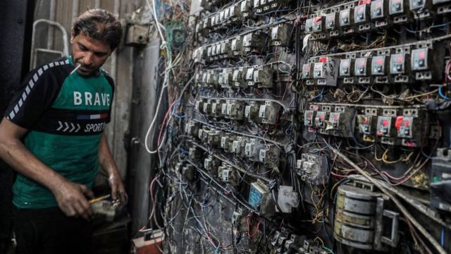 A technician is monitoring an electrical switchboard in a suburb of the Iraqi capital, Baghdad.