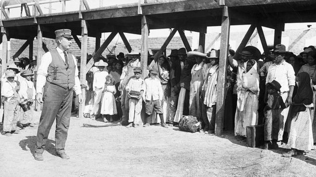 Un funcionario fronterizo estadounidense les habla a un grupo de refugiados mexicanos en el Puente Internacional de El Paso, en Texas. Año 1916.