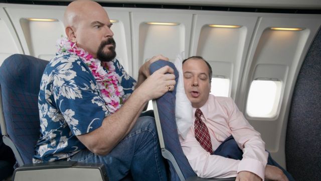 Un hombre muy incómodo en un asiento de avión