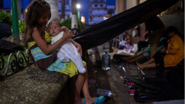 Una niña sostiene a un bebé en la caravana.