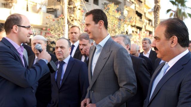 El presidente sirio, Bashar al Assad habla con un periodista durante un recorrido por el barrio de Damasco de Darayya