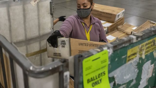 Работница почты разгружает ящики с почтовыми бюллетенями