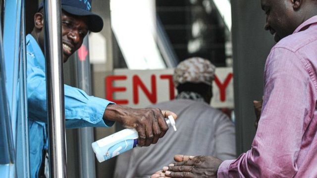 Un agent de sécurité donne du désinfectant pour les mains aux visiteurs par mesure de précaution à l'entrée d'un bâtiment à Nairobi, Kenya - 13 mars 2020