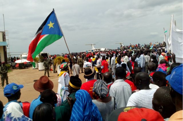 Crowds of people await President Salve Kiir's arrival at Juba airport from Khartoum