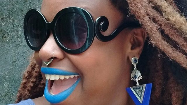 Fotografía de Joyce Fernandes con los labios pintados de azul eléctrico y unas gafas de sol.