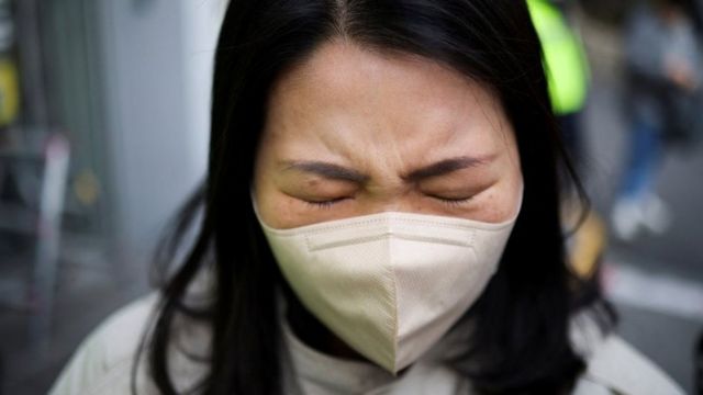 A woman with a face mask is crying with her eyes closed
