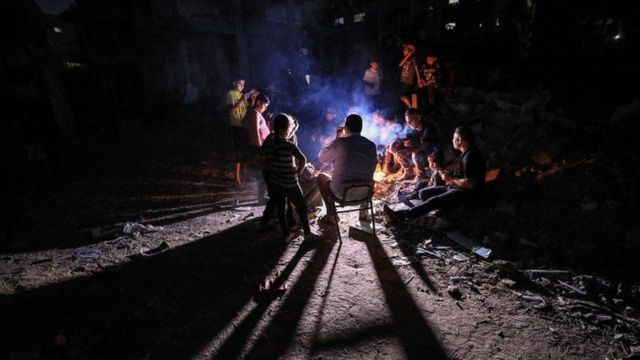 أشخاص يجلسون على حطام منزل مدمر في غزة