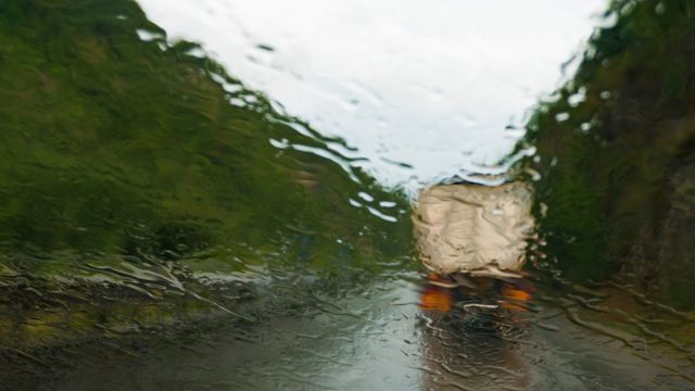 Un camión en la carretera, visto a través del parabrisas de un conductor bajo la lluvia