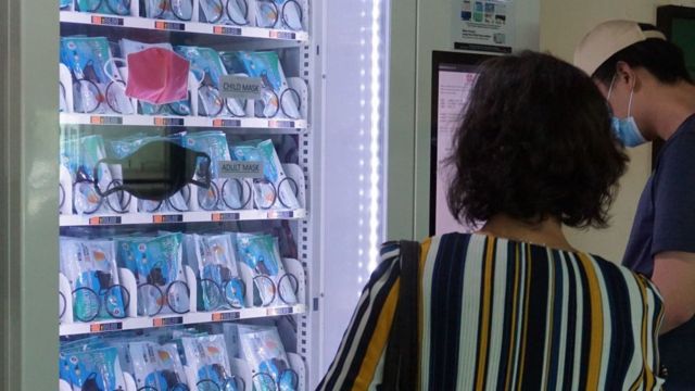 新加坡的一男一女在看着自动贩卖机中的口罩。