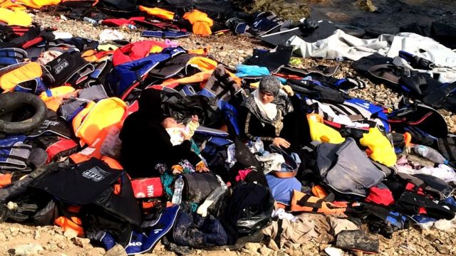 Migrantes rodeados de chalecos salvavidas
