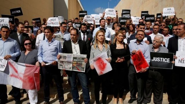 Journalists hold front pages and placards splattered in blood-red paint in Valletta, Malta. Photo: 19 October 2017