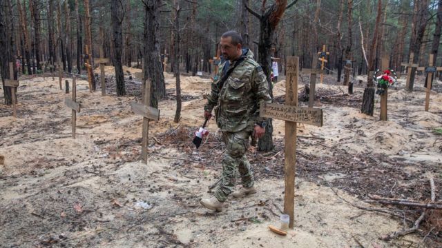 جندي يمشي بين قبور عثر عليها في غابة