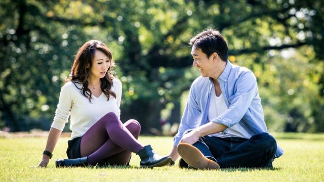 Japanese couple, sitting on the grass at a park in Tokyo, Japan