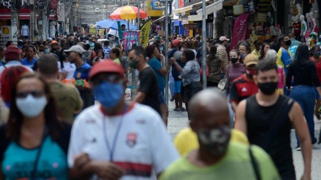 Pessoas em rua comercial movimentada usando máscaras de proteção contra a covid
