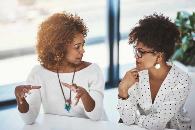 Dos mujeres jóvenes hablando y gesticulando.