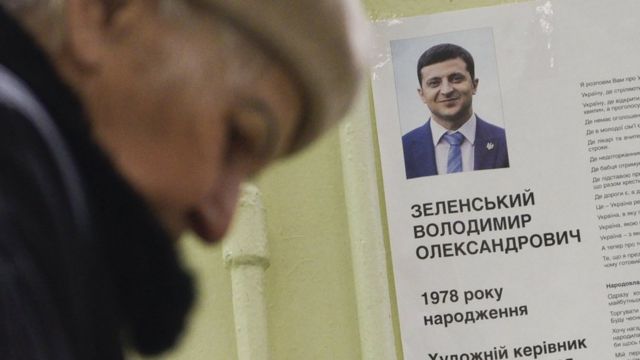 Жінка на виборчій дільниці, біля портрета Володимира Зеленського