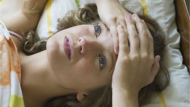 Una mujer acostada con cara de preocupación