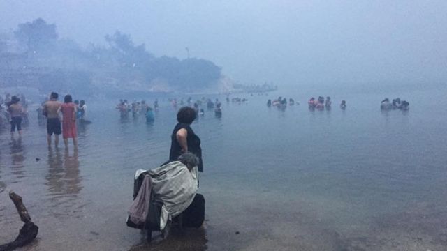 Pessoas fugindo do incêndio na Grécia pelo mar