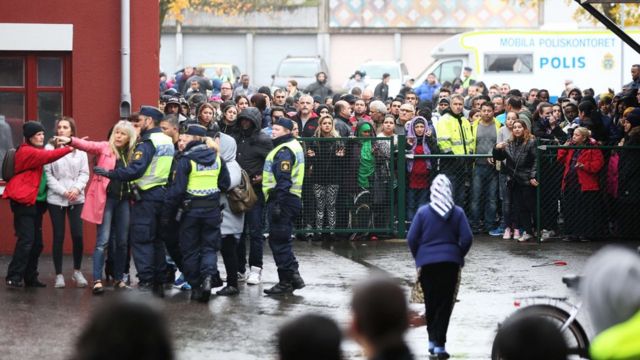Swedish police officers give information to people as they secured the area outside a primary and middle school in Trollhattan, southwestern Sweden (October 22, 2015,