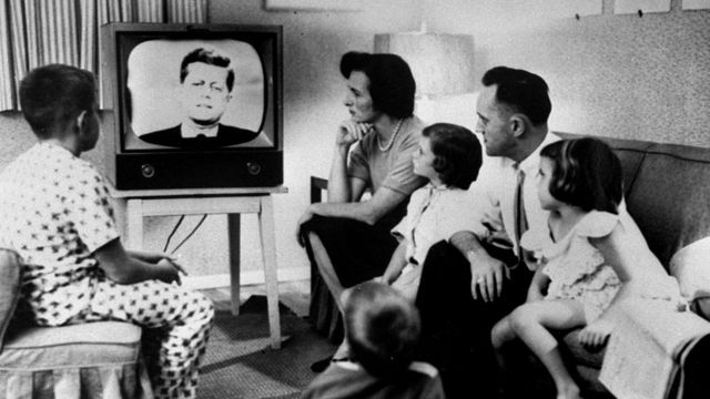 Familia estadounidense en los 60 con una imagen del presidente John F. Kennedy en el televisor.