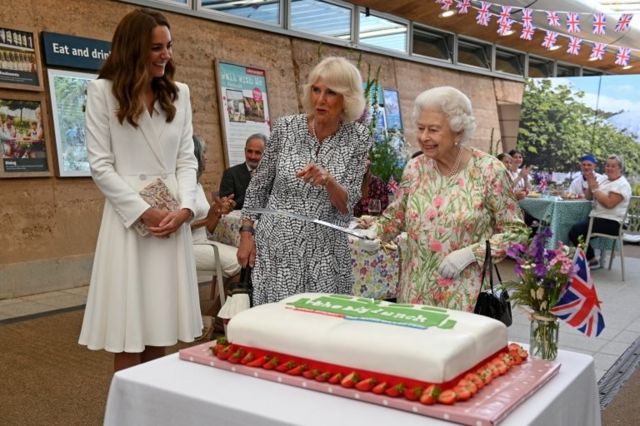 Queen Elizabeth holds a sword in order to cut a cake next to Catherine, the Duchess of Cambridge and Camilla, Duchess of Cornwall during a drinks reception on the sidelines of the G7 summit, at the Eden Project in Cornwall, Britain June 11, 2021