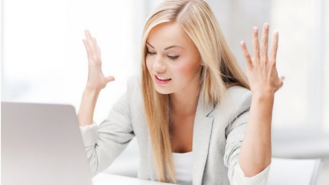 Mujer enojada ante una computadora portátil.