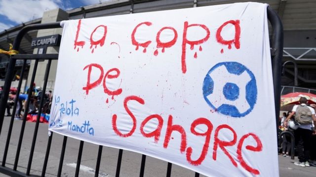 Cartaz pendurado em portão de estádio diz em espanhol: 'La copa de sangre'