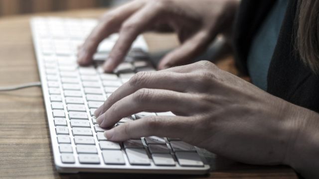 Mujer escribiendo en computador.