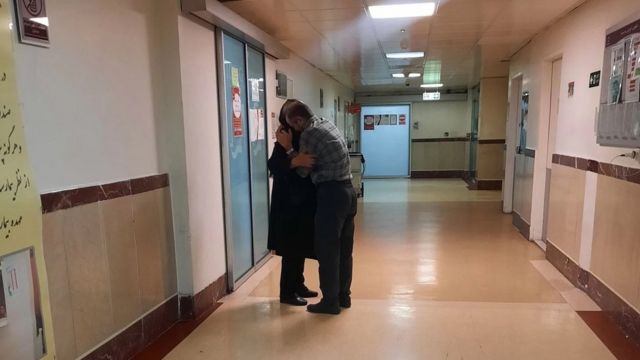 A man and woman embrace in a hospital corridor