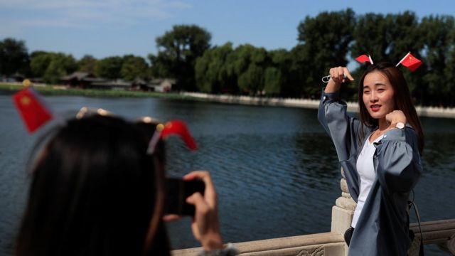 A woman poses for a photo in the tourist area around Houhai Lake during the China National Day holiday in Beijing, China, Oct. 2, 2020.