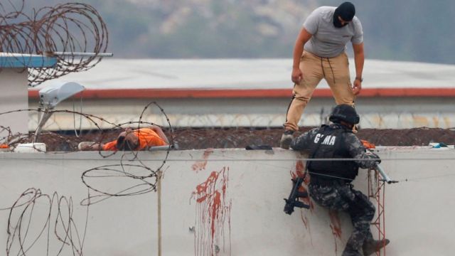 Policías junto al cuerpo de un reo en la cárcel de Guayaquil.