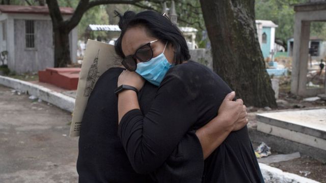 Dos personas abrazándose en un cementerio de México