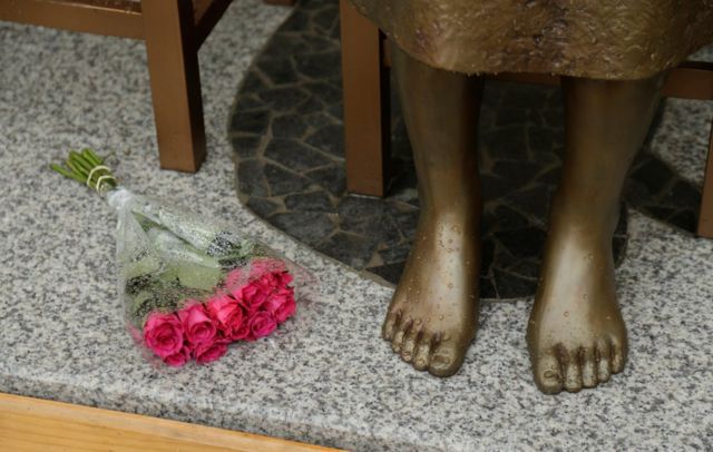 Flores a los pies de la estatua de una "mujer de confort" en Sídney.