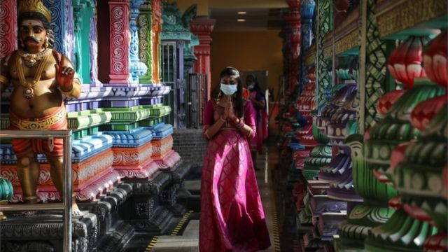 मास्क लगाएर मन्दिरभित्र प्रवेश गर्दै मलेशियाको क्वाल लाम्पुरस्थित एउटा मन्दिर
