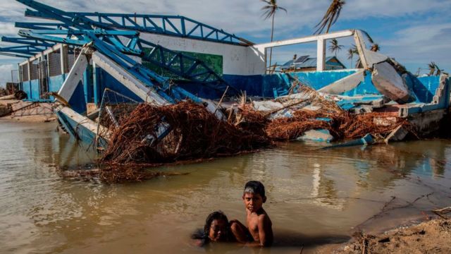 Crianças brincam em área alagada em meio a construção destruída por furacão na Nicarágua