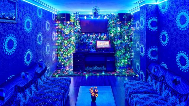 Sala de karaokê com paredes azuis e luzes coloridas