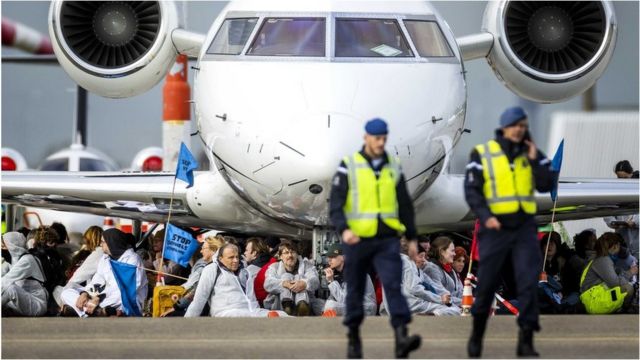 Los manifestantes se sientan debajo de un avión privado en el aeropuerto de Schiphol el 5 de noviembre.