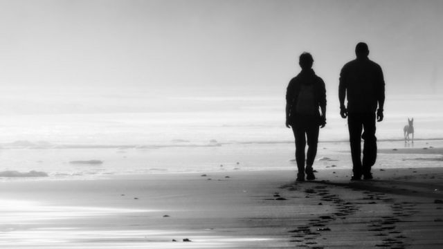 Un pareja en silueta caminando por la playa