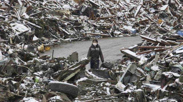 Un mujer camina entre los escombros en el pueblo japonés Minamisanriku, en el norte de Japón, tras el tsunami de 2011.