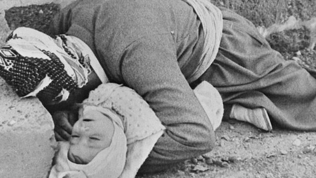 Un padre kurdo sosteniendo a su bebé en sus brazos.