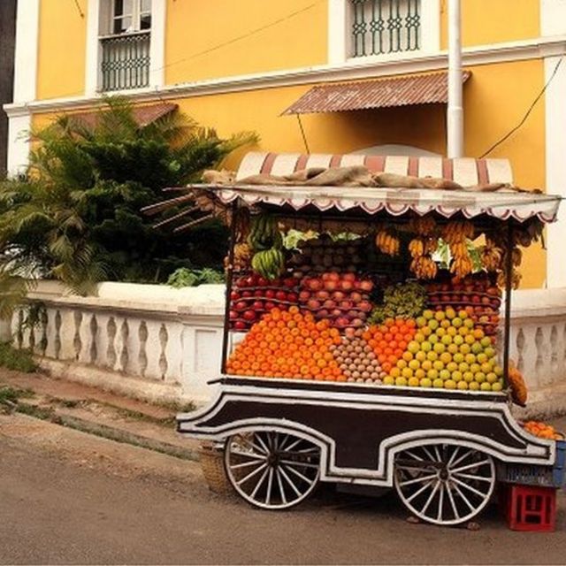 Yellow colonial house with fruit cart - loaded with mangoes - in front.