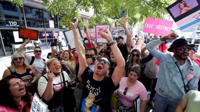 Pessoas com mãos levantadas e cartazes protestando na rua