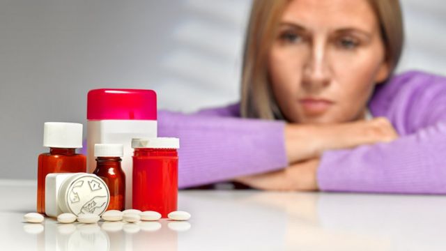 Mujer mirando a frascos de medicamentos