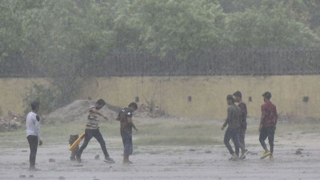 Boys play cricket on the street in Delhi under heavy rain in June 2021