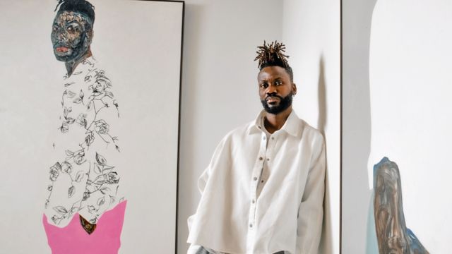 Amoako Boafo next to one of his self-portraits